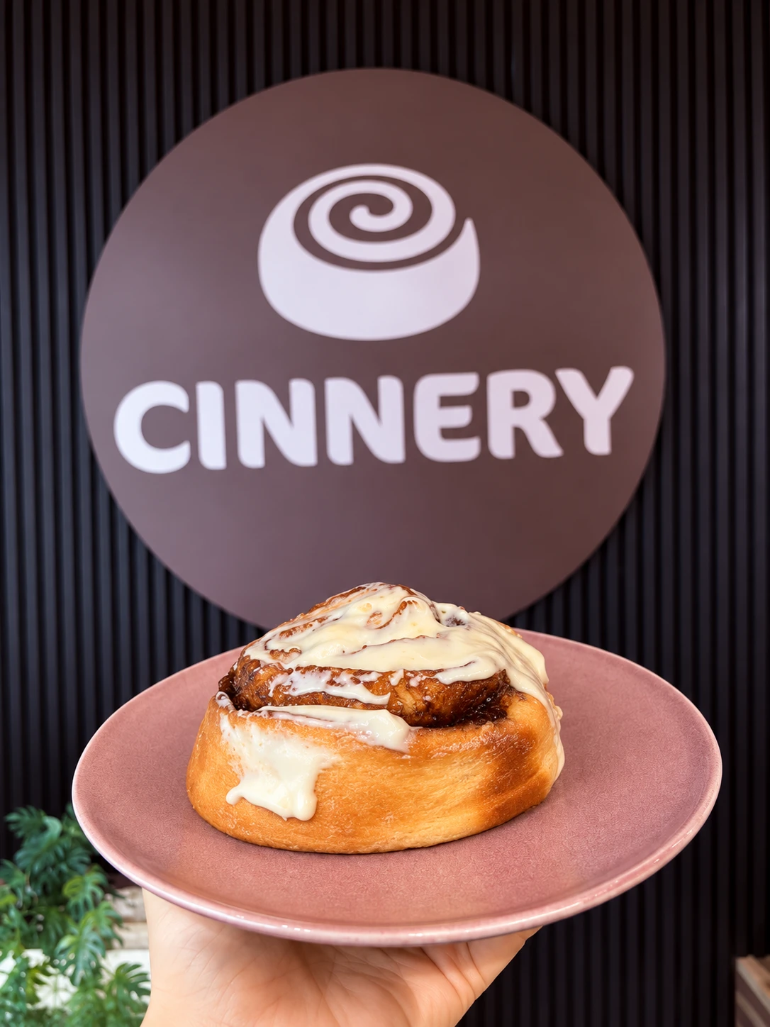 Cinnamon roll in front of the Cinnery sign